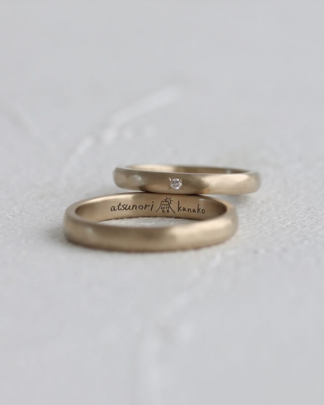 思い出の場所を刻印に。

おふたりが結婚の約束をされたという、
大切な思い出の場所。

当時のことを思い出しながら、
想いを込めて、丁寧に描いてくださいました。

温もりあふれる素敵な結婚指輪と共に、
末永くお幸せな日々を過ごされますように。
 
 
》左側
地金：K18CG
幅：2.8mm
仕上げ：ヘアライン
刻印：手書き刻印

》右側
地金：K18CG
幅：2.3mm
仕上げ：ヘアライン
刻印：手書き刻印
誕生石：ダイヤモンド
　
 
 
uchimari